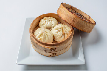 Shao Long Bao stuffed steamed and salted in a traditional Chinese steamer on a white background.