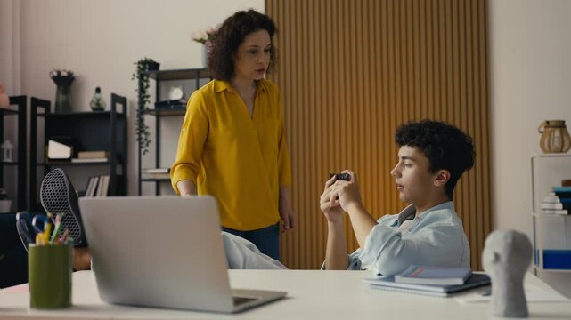 Mother scolding her teen son for playing games instead of studying, conflict