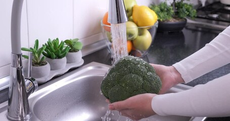 Woman hands washing fresh broccoli in the kitchen. Eating healthy raw organic food, vitamins, washing vegetables from pesticides concept. Slow motion 4k - Powered by Adobe