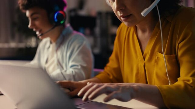 Excited mother and her teen son playing a video game on laptops as a team
