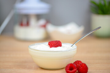 white yogurt on the table with raspberries close-up, healthy breakfast in the kitchen