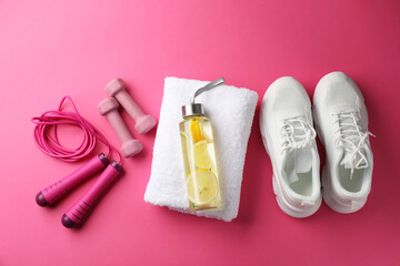 Lemon water in bottle and fitness equipment on pink background, flat lay
