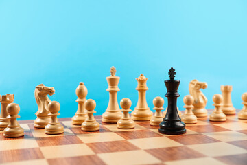 Black king in front of other white chess pieces on chessboard. Competition concept