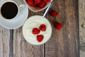 white yogurt on the table with raspberries close-up, healthy breakfast in the kitchen
