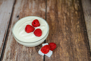 white yogurt on the table with raspberries close-up, healthy breakfast in the kitchen