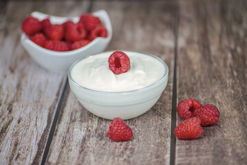 white yogurt on the table with raspberries close-up, healthy breakfast in the kitchen