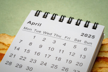 April 2025 - small spiral desktop calendar, time and business concept