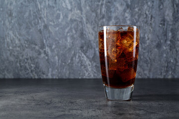 Sweet soda water with ice cubes in glass on grey table, space for text