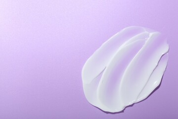 Cream sample on violet background, top view. Space for text