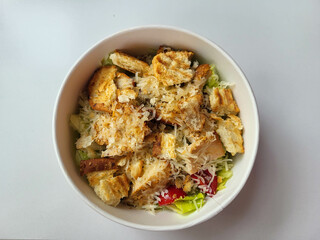 Caesar salad with croutons in a paper disposable bowl on the table.