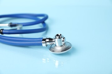 Stethoscope on light blue background, closeup. Space for text