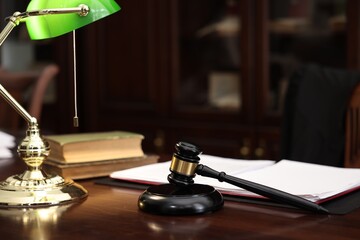 Judge workplace with gavel, lamp, documents and books in office