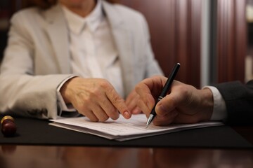 Notary showing client where to sign document in office, closeup