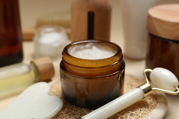 Different body care products and massaging tools on beige background, closeup
