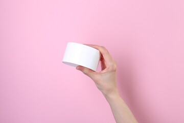 Woman with jar of cream on pink background, closeup. Body care product