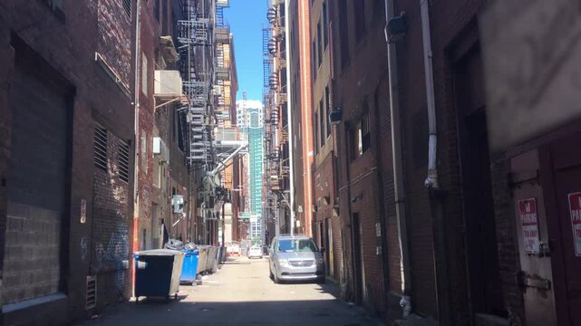 A static handheld view of an alley in a large city in the summer.  	