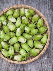 Hazelnut harvest - fresh, green hazelnuts on a gray wooden board background.