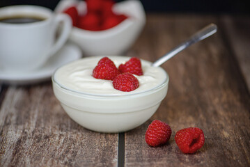 white yogurt on the table with raspberries close-up, healthy breakfast in the kitchen