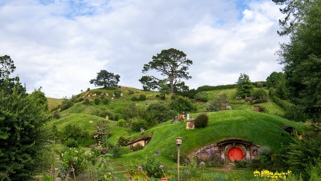 A lush green landscape featuring Hobbiton movie set with hobbit houses in Matamata, New Zealand