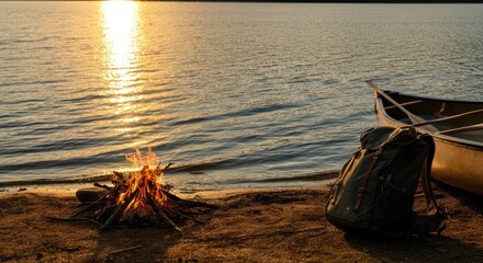 Sunset by lake with campfire, canoe, and backpack