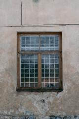 Obraz premium Historic Grilled Window on a Peeling and Crumbling Facade. Mysterious Forgotten House with a Worn-Out Window Frame