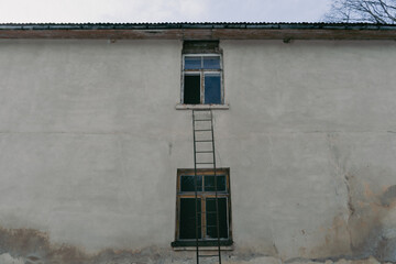 Abandoned House with a Rusty Ladder Leading to an Open Window. Forgotten House with a Suspicious...