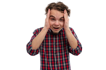 Fototapeta premium A young man with curly hair expressing surprise while holding his head with both hands against a white background.