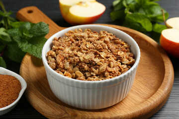 Delicious apple crisp in bowl and ingredients on black table, closeup