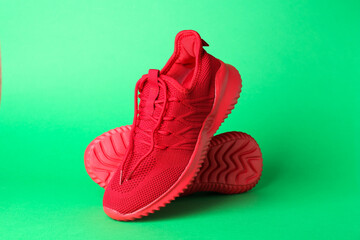 Pair of stylish red sneakers on green background