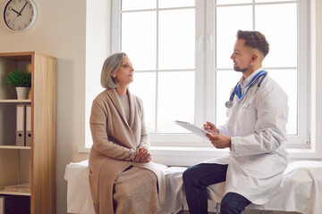Obraz premium Aged woman consults with doctor rehabilitologist. With compassion and expertise man doctor physician guides aged woman through her medical concerns Aged woman visiting doctor rehabilitologist