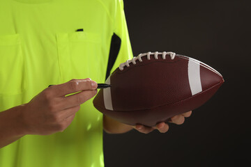 Professional player signing autograph on American football ball black background, closeup