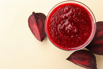 Fresh beetroot smoothie in glass and cut vegetable on beige background, flat lay. Space for text