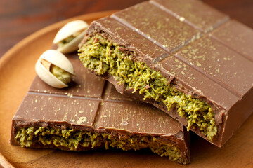 Pieces of tasty Dubai chocolate with pistachios and knafeh on wooden table, closeup
