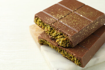 Pieces of tasty Dubai chocolate with pistachios and knafeh on white wooden table, closeup. Space for text