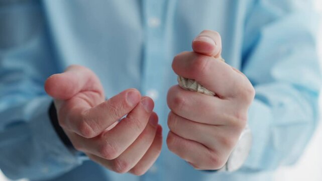 An office worker in a blue shirt crumples a sheet of paper in his hands.
Crumpled paper in the hands of a man.
A man stands in a bright office and crumples paper.
Paper ball in hands.
Ball from paper