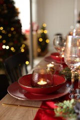 Christmas place setting with festive decor on wooden table in room, closeup