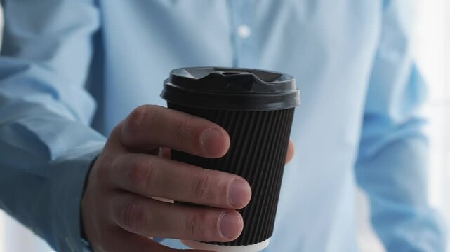 An office worker holds a glass of coffee in his hands.
A man drinks coffee.
Black coffee glass.
Americano in the hands of a man.
Morning coffee.
Coffee break at work