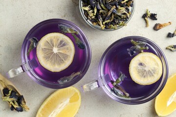 Delicious butterfly pea flower tea with lemon on gray textured table, flat lay