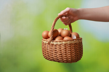 Woman with basket of eggs on blurred background, closeup. Space for text