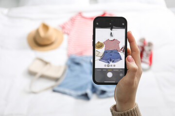 Woman with smartphone taking photo of her used clothes indoors, selective focus