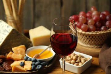 Red wine and different snacks served on table, closeup