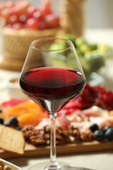 Red wine and different snacks served on table, closeup