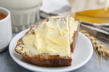 Slices of bread with butter, honey, milk and spike on light grey table, closeup
