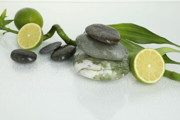 Spa composition with limes, massage stones and bamboo stem on wet surface