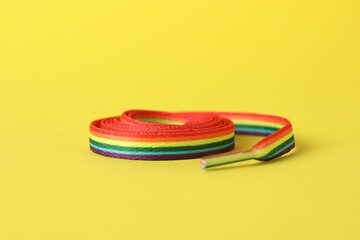 Shoelace in LGBT colors on yellow background, closeup