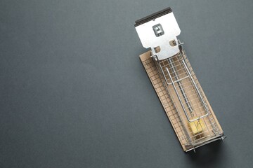 Metal mouse trap with piece of cheese on gray background, top view. Space for text