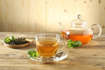 Freshly brewed tea in glass cup and teapot on wooden table