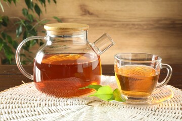 Freshly brewed tea in glass cup and teapot on table