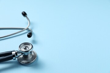 Stethoscope on light blue background, closeup. Space for text