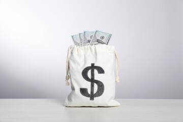 Dollar banknotes in burlap sack on white table